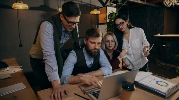 A team of professionals collaborating on a laptop in a digital marketing agency in Abu Dhabi, focused on strategic planning and analytics.